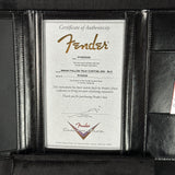 A close-up of a black leather Fender instrument case opening to reveal a Certificate of Authenticity insert. The certificate is printed on textured white paper with gold and black text, featuring the Fender logo and details for a Brian Fallon Tele Custom Jnr in black.