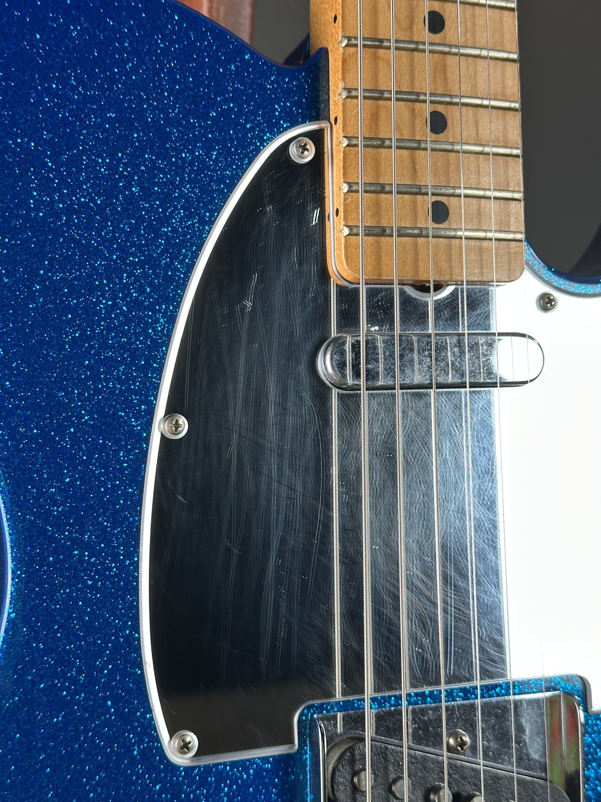Close-up of a blue electric guitar with a focus on the neck and body.