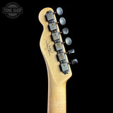 Close-up of the headstock of an electric guitar with a light natural wood finish and six silver tuning pegs, shown against a solid black background. A Tone Shop watermark is visible in the top left corner.