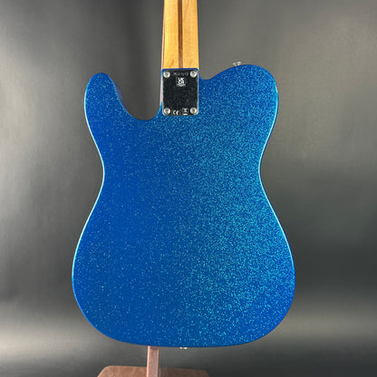 Blue glittery guitar body on a stand with a gray background