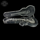 An open black guitar hard case on a black background, containing a dark wood electric guitar. A Tone Shop logo watermark is visible in the top left corner.