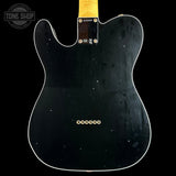The back of a black Fender Telecaster electric guitar, showing the glossy black body, white edge trim, gold hardware, and a yellow neck joint against a black background.