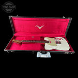 A white electric guitar with a cream pickguard and maple neck, displayed inside an open black hard case with bright pink velvet lining. A Tone Shop watermark is visible in the top left corner.