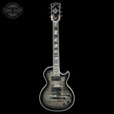 A Gibson Les Paul Custom electric guitar with a dark gray to black flamed maple finish, featuring white binding and white block inlays on the fretboard, shown against a solid black background.