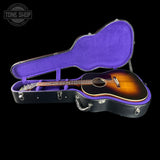 Acoustic guitar in a black and purple case with 'Tone Shop' logo.