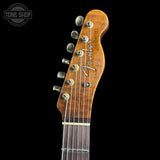 Close-up of the headstock of a Fender Stratocaster electric guitar, showing the wood grain, six tuning pegs, and the Fender logo, set against a solid black background.