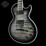 A close-up of an electric guitar body with a dark flamed maple finish, featuring a black and gray wood grain pattern, white edge binding, and chrome hardware, shown against a solid black background.