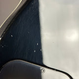 Close-up of a glossy black and white surface with visible scratches and scuffs, likely a vehicle panel or metal body part.