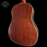 Back view of a wooden acoustic guitar with a dark brown finish on a black background.