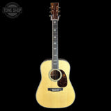 A natural wood acoustic guitar with a dark fretboard and pickguard, shown vertically against a solid black background. A circular 'TONE SHOP' watermark is visible in the top-left corner.