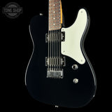 A black electric guitar with a white pickguard and chrome hardware, shown against a solid black background with a Tone Shop watermark in the upper left corner.
