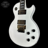 White electric guitar with a black pickguard on a black background, featuring the 'Tone Shop' logo.