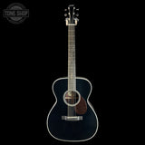 A dark navy blue acoustic guitar with a glossy finish, featuring a brown pickguard and white binding, shown against a solid black background with a Tone Shop logo in the top-left corner.