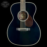 A close-up studio shot of an acoustic guitar body against a black background, showing a glossy dark blue finish, white binding, a brown pickguard, and part of the neck. A Tone Shop watermark is visible in the top-left corner.