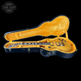 Gold electric guitar in an open black case with a visible 'Tone Shop' logo.
