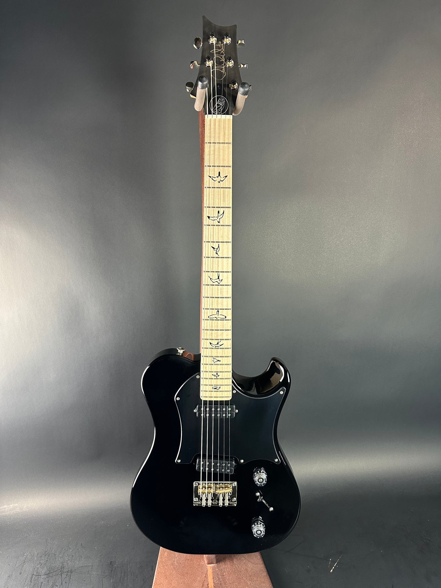 Black electric guitar on a gray background