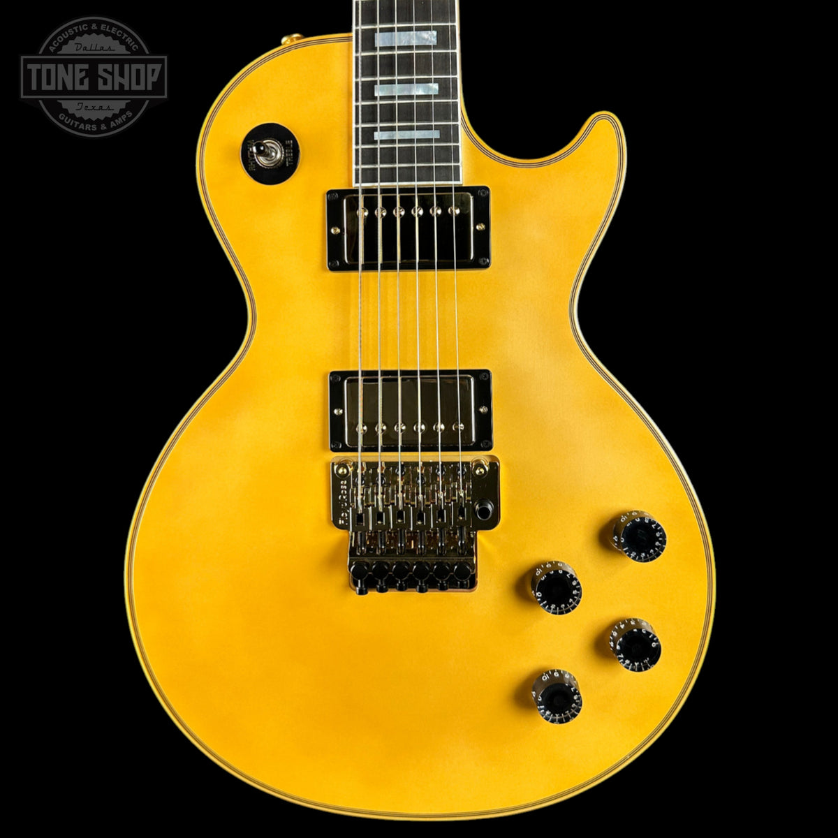 Yellow electric guitar with a black pickguard on a black background, featuring the Tone Shop logo.