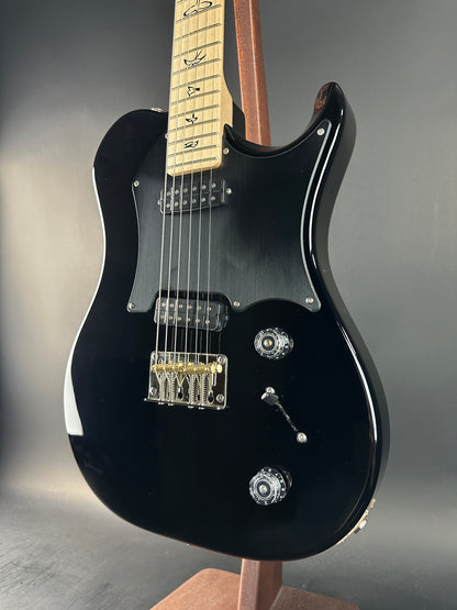 Black electric guitar on a gray background