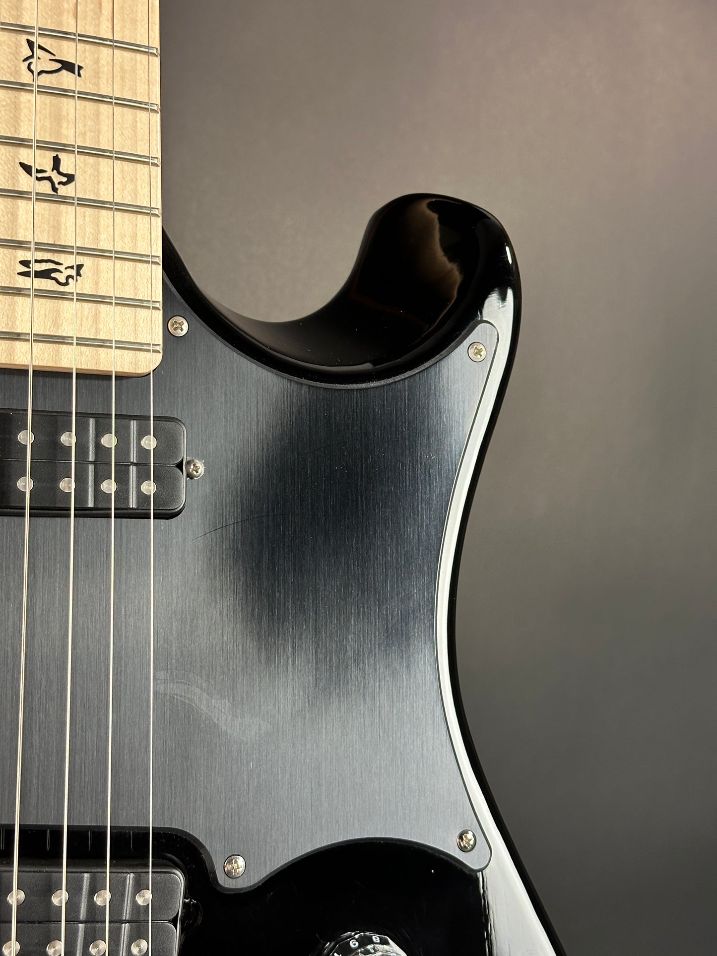 Close-up of a black electric guitar with a metallic finish on a dark background