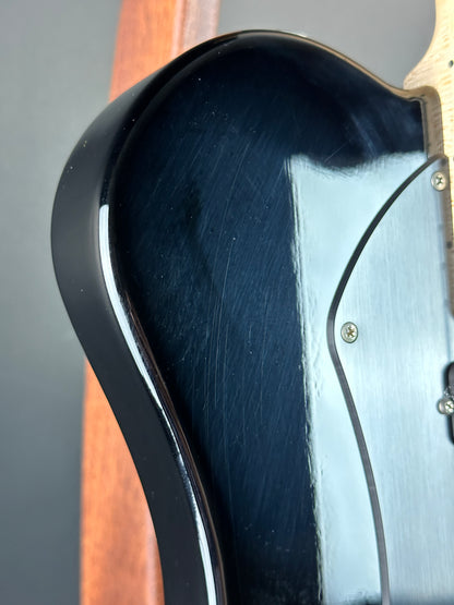 Close-up of a guitar's black pickguard with a wooden neck.