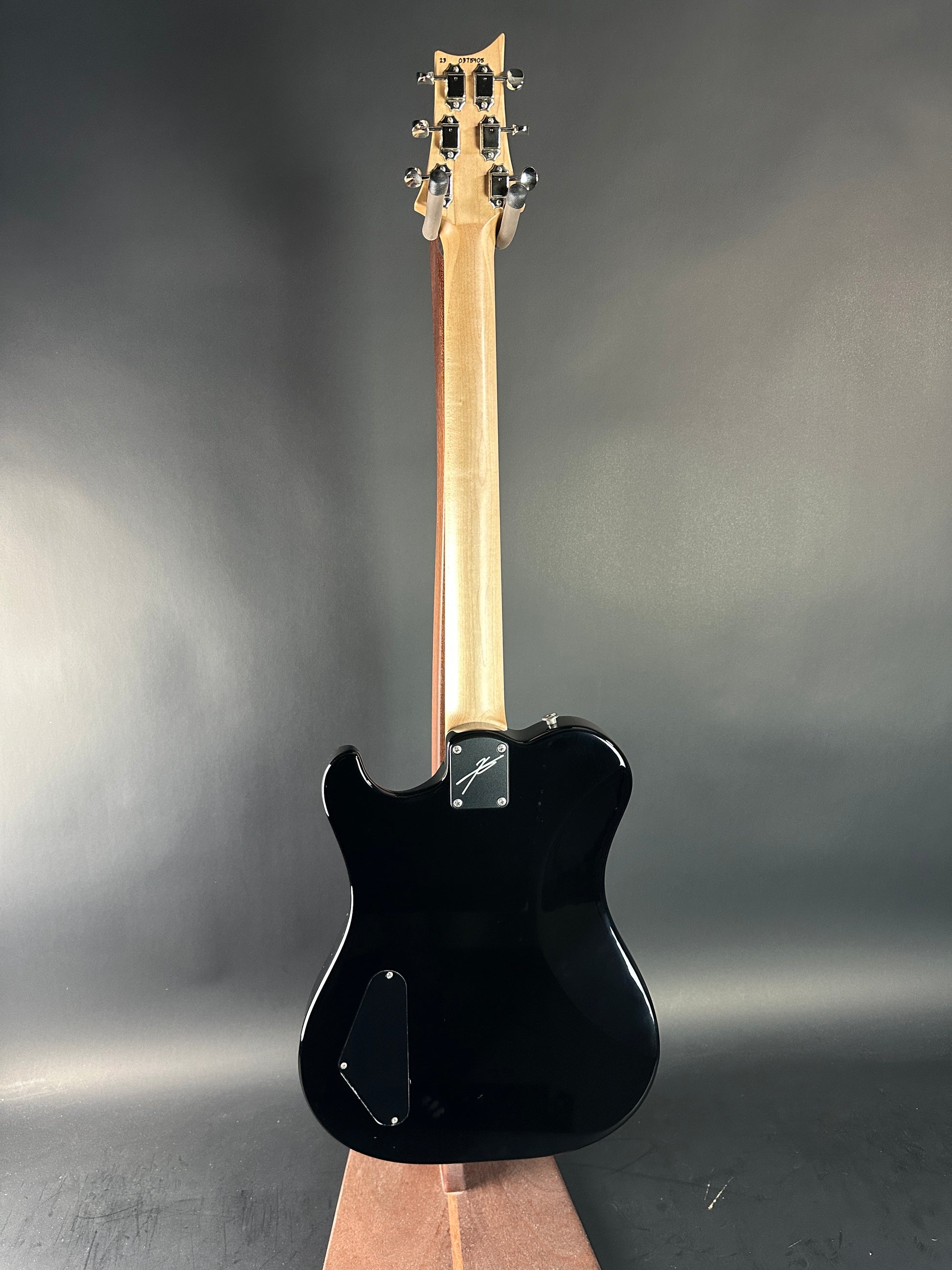 Black electric guitar with a wooden neck on a dark gray background