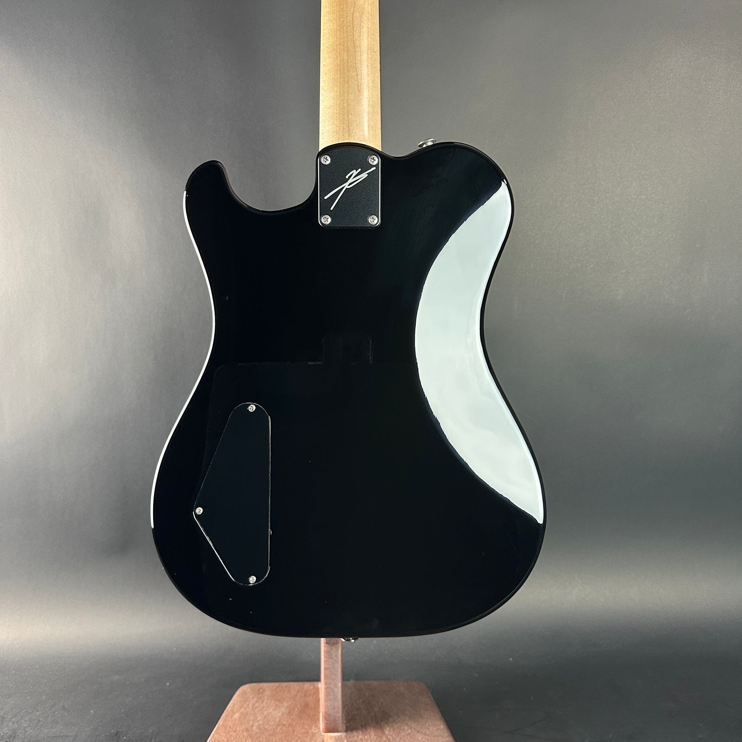 Black electric guitar with a wavy design on a gray background