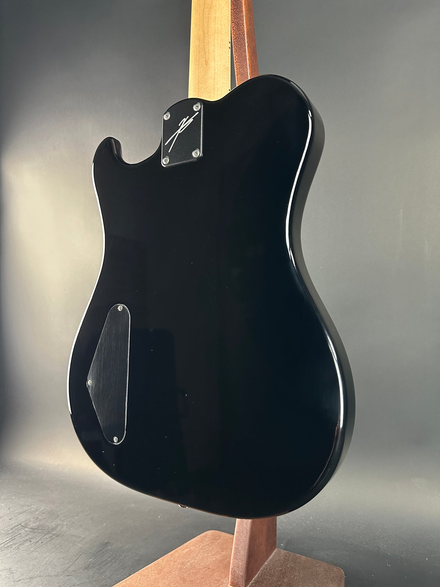 Black electric guitar body on a gray background
