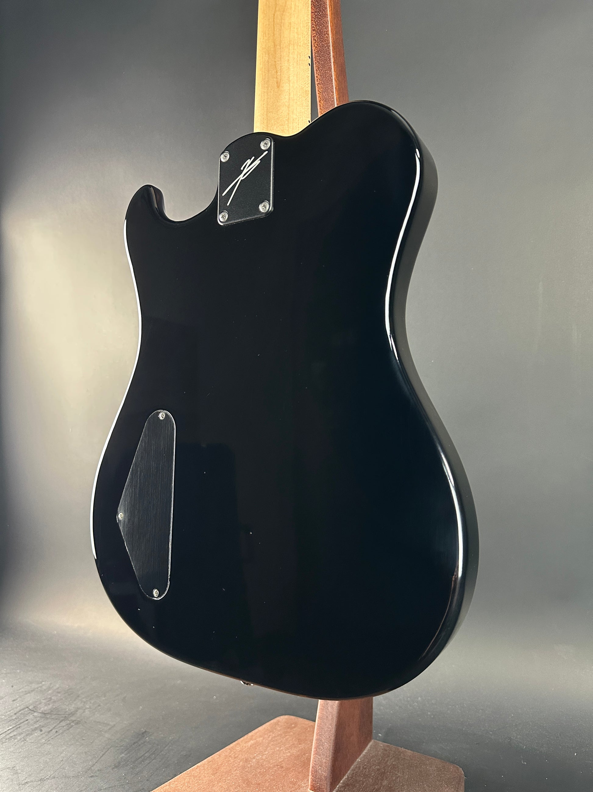 Black electric guitar body on a gray background
