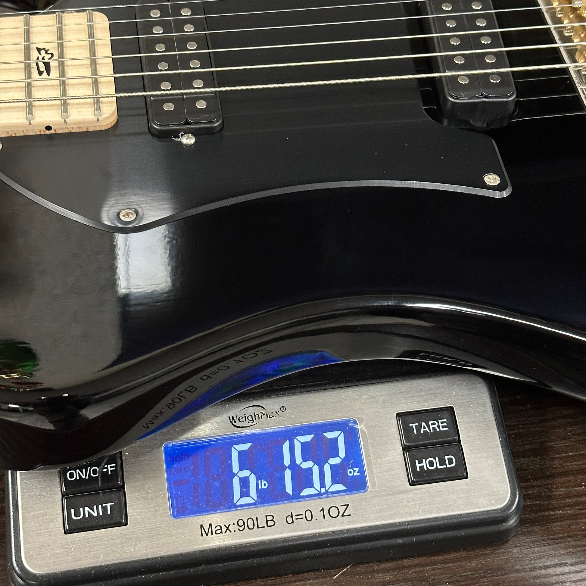 Black electric guitar on a digital scale displaying weight