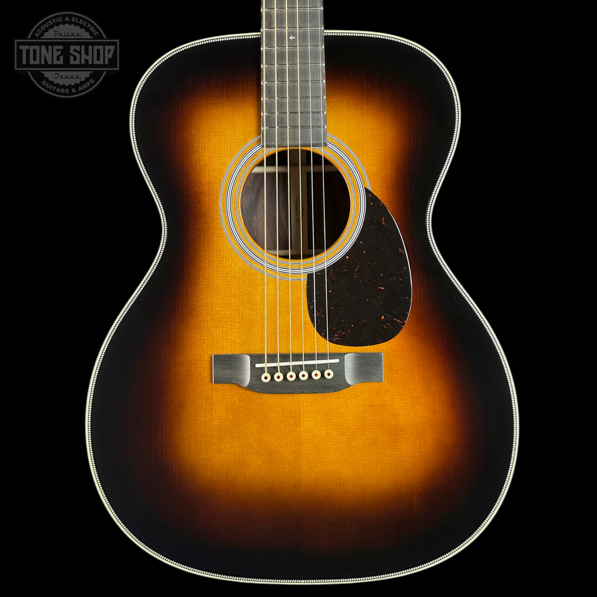 An acoustic guitar with a classic sunburst finish, featuring a bright orange center fading to a dark black edge, shown against a solid black background.
