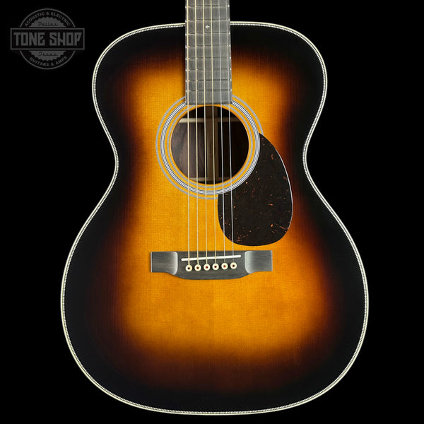 An acoustic guitar with a classic sunburst finish, featuring a bright orange center fading to a dark black edge, shown against a solid black background.