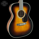 A close-up studio shot of an acoustic guitar body against a black background, showing a classic sunburst finish that transitions from dark brown to warm amber and black. The brand 'Tone Shop' is visible as a watermark in the top-left corner.