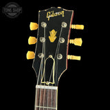 Gibson guitar headstock with yellow tuning pegs on a black background
