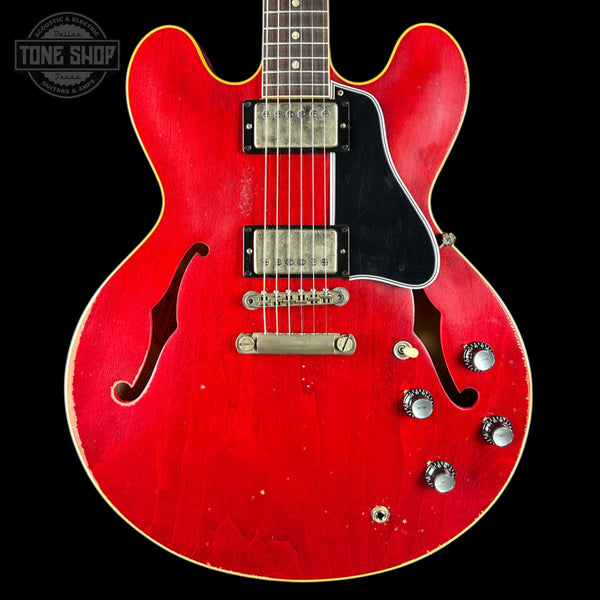 Red electric guitar with a black pickguard on a black background, featuring the 'Tone Shop' logo.