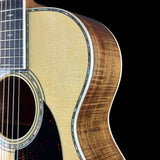 Close-up of an acoustic guitar showing the natural wood soundboard, floyd top, and part of the fretboard against a black background.