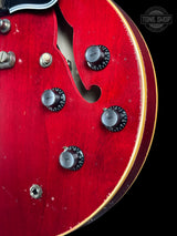 Close-up of a red guitar with control knobs on a black background, featuring 'Tone Shop' logo.