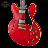 Red electric guitar with a black pickguard on a black background, featuring 'Tone Shop' logo.