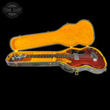 Electric bass guitar in an open case with 'Tone Shop' branding.