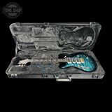 An electric guitar with a blue-green flame finish body and black neck, displayed inside an open black hard case with custom foam padding. The Tone Shop logo is visible in the top left corner.