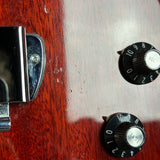 Close-up of a guitar's control knobs and tuning peg on a wooden surface.