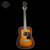 A Martin acoustic guitar with a classic sunburst finish, shown vertically against a solid black background. The brand logo 'Martin' is visible on the headstock.