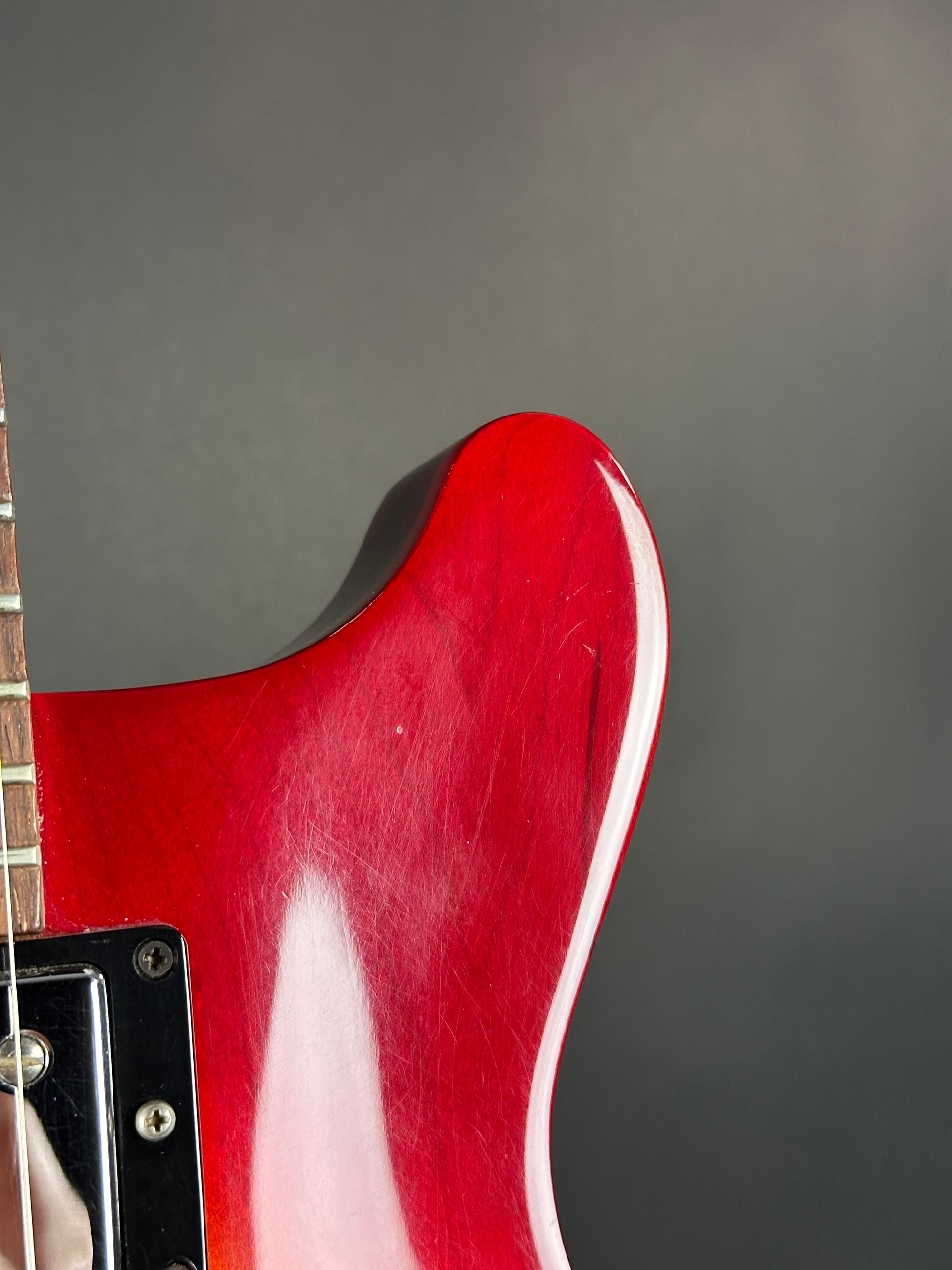 Close-up of a red electric guitar's neck against a gray background