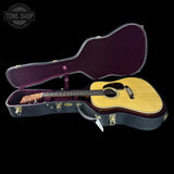 Acoustic guitar in an open case with 'Tone Shop' logo in the corner.