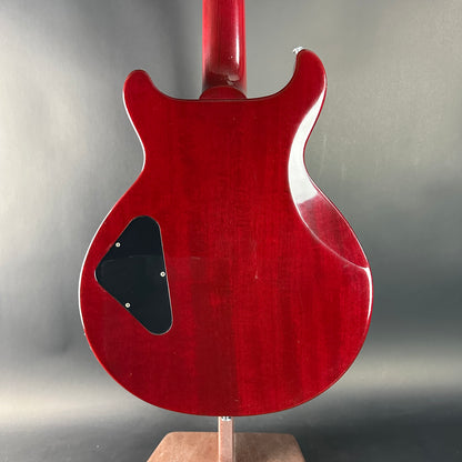Red electric guitar on a stand against a gray background