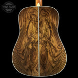 Close-up of a wooden acoustic guitar back with 'Tone Shop' logo.
