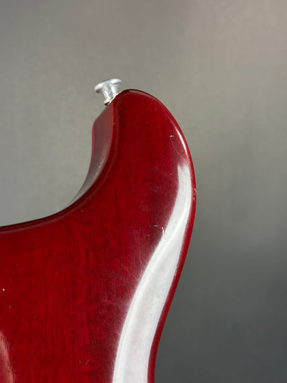 Close-up of a red guitar neck with a clear label on a gray background