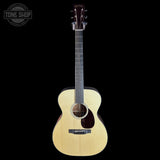 A natural wood acoustic guitar with a cutaway body, dark fretboard, and headstock, shown against a solid black background. A 'TONE SHOP' watermark is visible in the top-left corner.