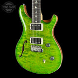 A green flamed maple electric guitar with a black body, silver hardware, and a dark fretboard, shown against a black background with a Tone Shop watermark in the top left corner.