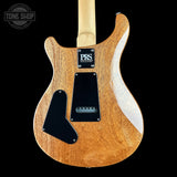 The back of a PRS electric guitar with a natural wood finish and black pickguard, shown against a solid black background with a Tone Shop watermark in the top left corner.