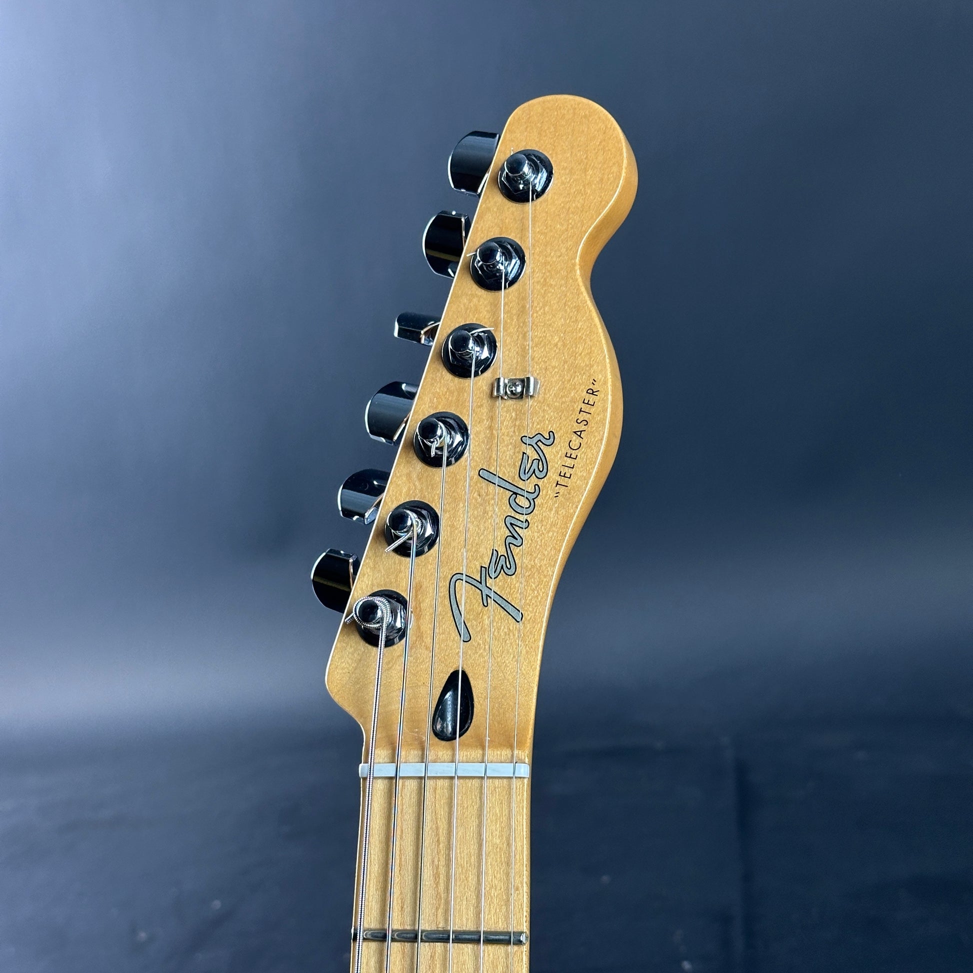 Close-up of a Fender Telecaster guitar headstock on a dark background
